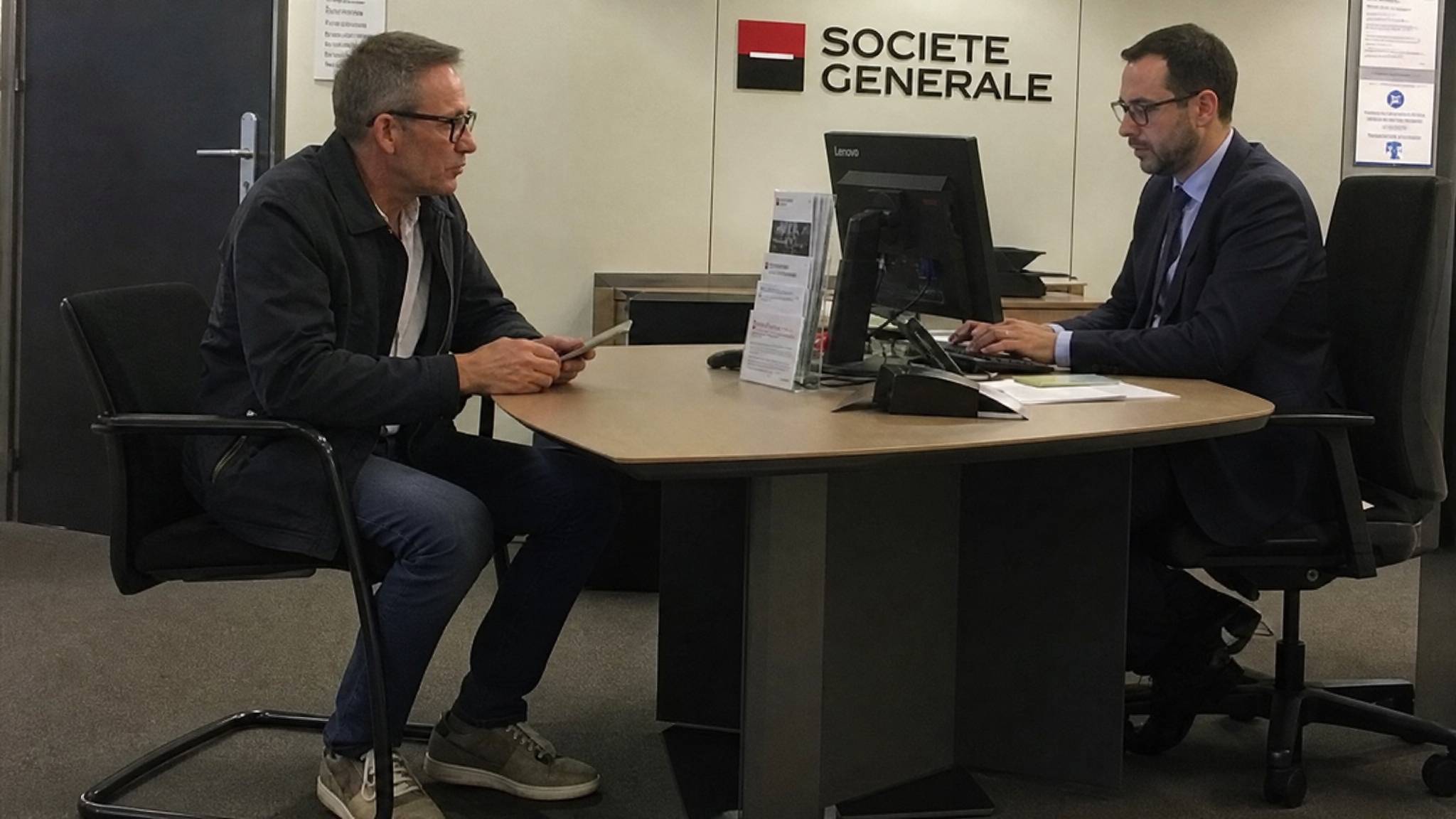 Julien Courbet en tenue ordinaire face au conseiller de l'agence Société Générale